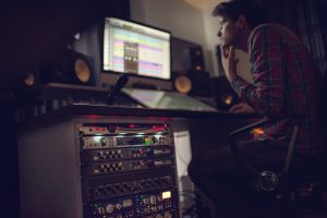 Audio rack in recording studio with producer in the background.